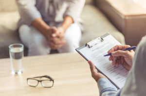 Doctor is making notes while listening to his patient