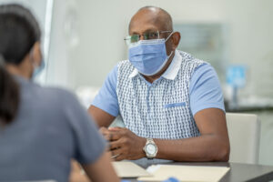 Man wearing mask talking to doctor