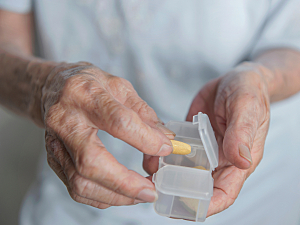 Close up of senior woman holding a medicine box and taking out a pill