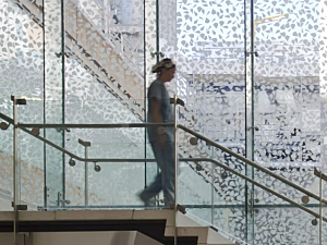 Nurse walking down staircase with glass walls in background