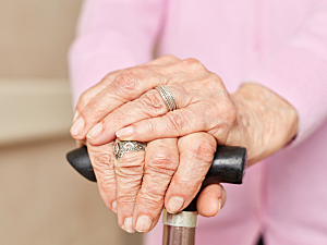 Hands of senior woman resting on cane handle