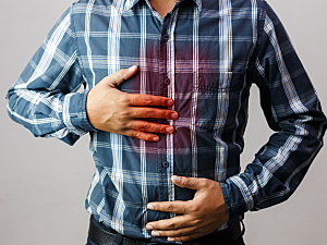 Man holding chest with red highlight to indicate discomfort from reflux symptoms