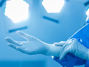 Close up of surgeon putting on blue gloves in operating room