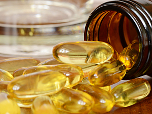 Yellow oil capsules spilling out of brown bottle onto table