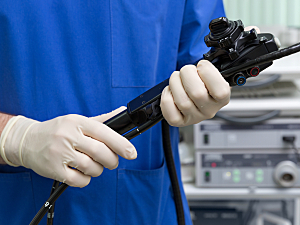 Gastroenterologist holds black endoscope device in hospital setting