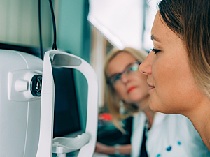 Female patient at ophthalmologist leaning toward machine for optical coherence tomography testing