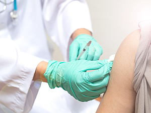 Close up of doctor administering flu shot to patient's shoulder