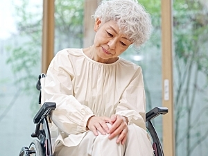 Eldery woman in wheelchair feeling arthritis discomfort in right knee