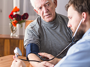 Doctor monitoring blood pressure of older male patient, hypertension concept