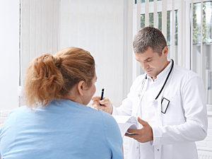 Obese female patient consulting with male doctor in white coat, looking at clipboard