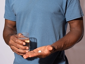man holding a glass of water and medication