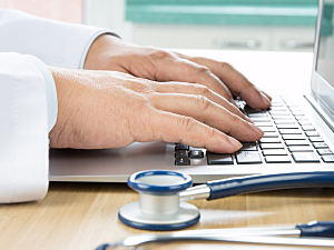 Close up of doctor's hands on keyboard of laptop, electronic health record concept