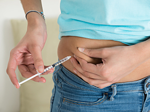 Close up of woman injecting insulin into stomach
