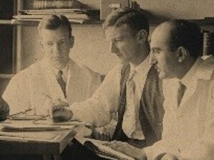 Claude Beck, Eliot Cutler, Samuel Levine sitting at desk looking at papers, doctors working as team